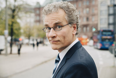 Portrait of smiling businessman wearing suit while standing in city