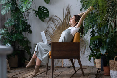 Calm italian female freelance gardener with closed eyes relaxing while at her cozy home garden