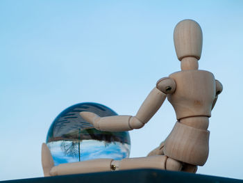 Close-up of crystal ball and figurine against sky