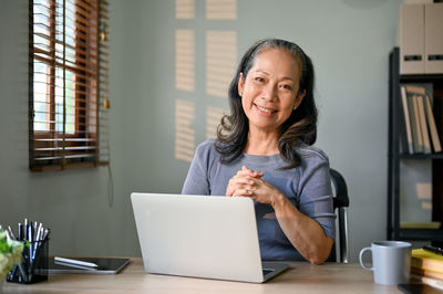 Portrait of young woman using laptop at office