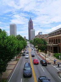 Vehicles on road amidst buildings in city against sky