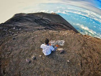 Man sitting on rock by sea