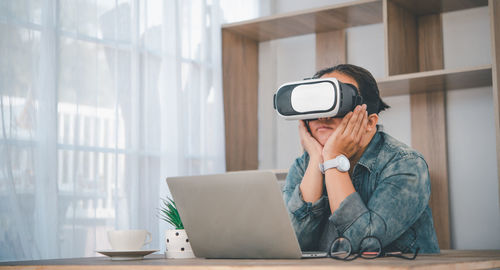 Woman with hand on chin wearing virtual reality simulator at home