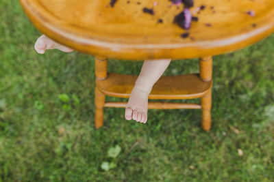 One year old feet sticking out of wooden highchair at cake smash