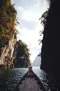 Long tail boat ride among limestone islands in lake against sky