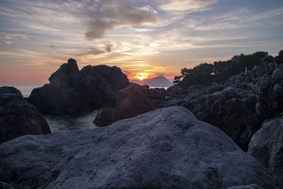 Rock formation in sea against sky during sunset