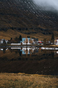 Scenic view of lake by buildings against mountain