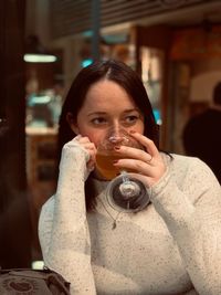 Young woman drinking wine while sitting in restaurant