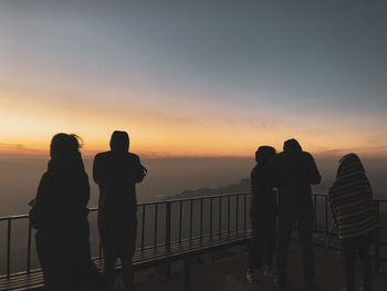 People standing at observation point against sky during sunset