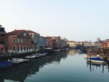 Sailboats moored in canal against buildings in city