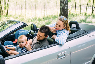 Mom, dad and little son in a convertible car. summer family road trip to nature