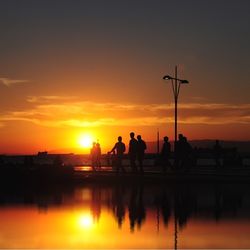 Silhouette of people in water at sunset