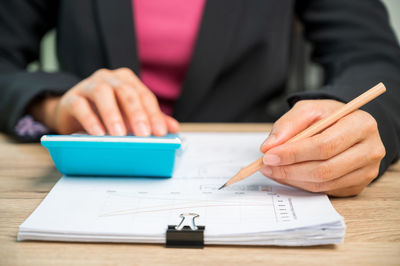 Midsection of man holding paper at table