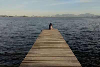 Rear view of woman on pier at sea