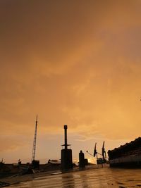 Silhouette of factory against sky during sunset