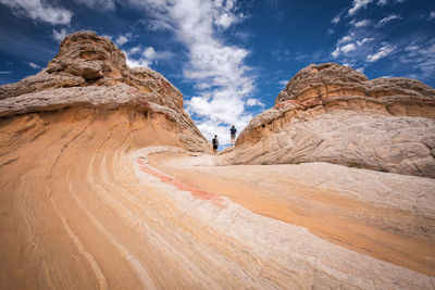 Men walking on rock against sky