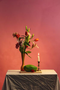 Close-up of red flower vase on table against wall