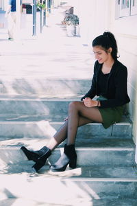 Young woman sitting on staircase outdoors