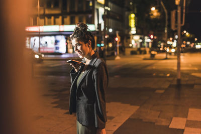 Woman standing on footpath at night