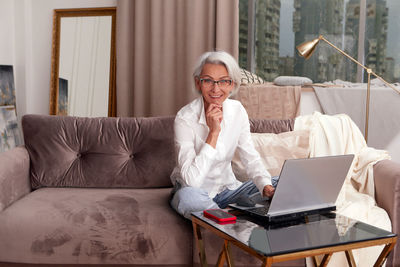 Portrait of businesswoman using laptop sitting on sofa at home
