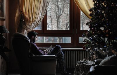 Rear view of man sitting on sofa at home in christmas