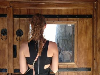 Rear view of woman standing on wooden floor