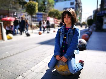 Girl kneeling on sidewalk in city