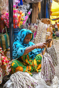 Full length of woman sitting at market stall