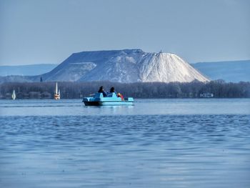 Rear view of boating in calm lake