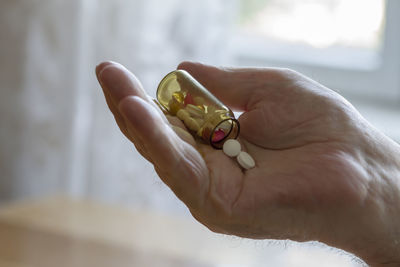 Cropped hand holding pills at home