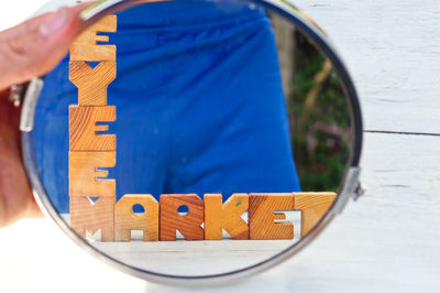 Cropped hand holding mirror with reflection of man and text