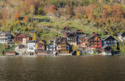 Houses by lake against buildings during autumn