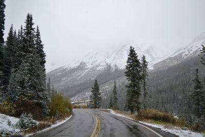 Road amidst snow covered mountains against sky