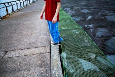 Low section of woman standing on wet footpath