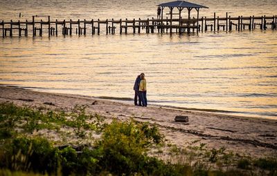 Rear view of man standing on pier at beach