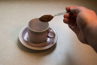 Hand holding coffee cup on table