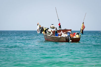 People on boat sailing in sea against clear sky