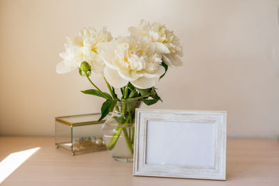 Portrait white picture frame mockup on wooden table.