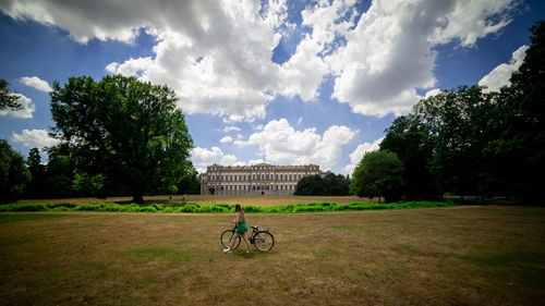 People riding bicycle on field against sky