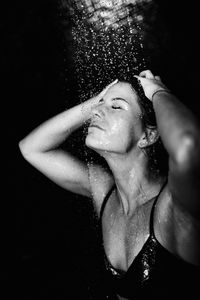 Mid adult woman taking shower in bathroom