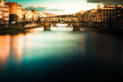 Arch bridge over river against buildings in city