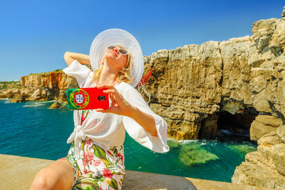 Woman taking selfie through mobile phone at beach