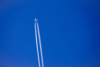 Low angle view of airplane flying against clear blue sky