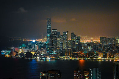 Illuminated modern buildings in city against sky at night