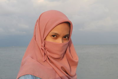 Portrait of young woman wearing hijab against sea