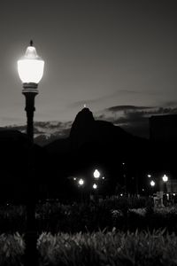 Illuminated street light against sky at dusk