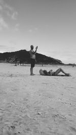 Full length of men walking on sea shore against sky