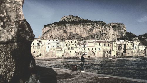 People standing by sea against sky in city