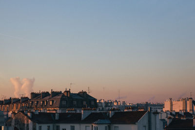 Buildings in city against clear sky during sunset