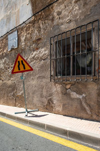 Road sign by wall